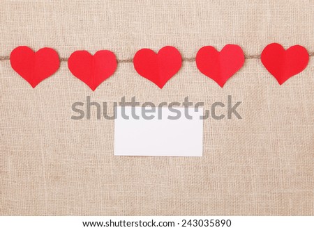 Valentine's Day background with red paper hearts on  burlap background
