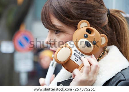MILAN - MARCH 2: Woman poses for photographers before Giorgio Armani show with Moschino bear smartphone cover, Milan Fashion Week Day 6, Fall/Winter 2015/2016 street style on March 2, 2015 in Milan.