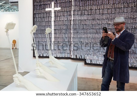 TURIN, ITALY - NOVEMBER 6: Artissima, contemporary art fair opening with people, galleries and art collectors on November 6, 2015 in Turin, Italy. Man photographs with smartphone white art installation.