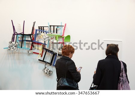 TURIN, ITALY - NOVEMBER 6: Artissima, contemporary art fair opening with people, galleries and art collectors on November 6, 2015 in Turin, Italy. Women looking at art installation with chairs.