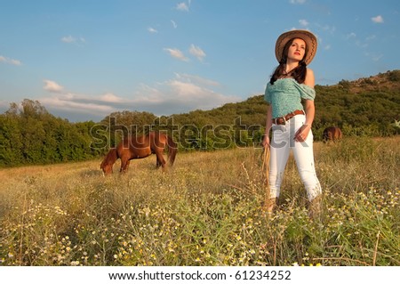 beautiful young woman in a field, the horse is grazing, open space, cowboy