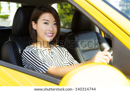 A charming Asian lady driving a yellow car.