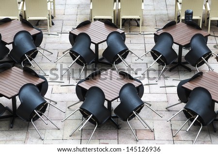 A outdoor restaurant with black plastic chairs not open for business yet