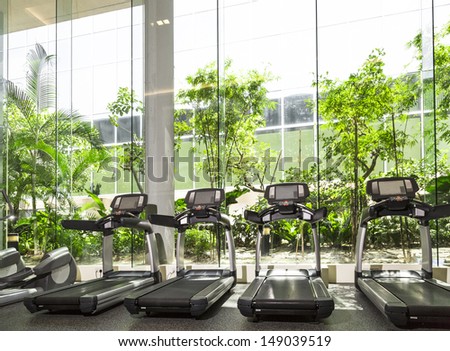 Four Treadmill In A Gym With High Ceiling In Front Of A Big Glass Window