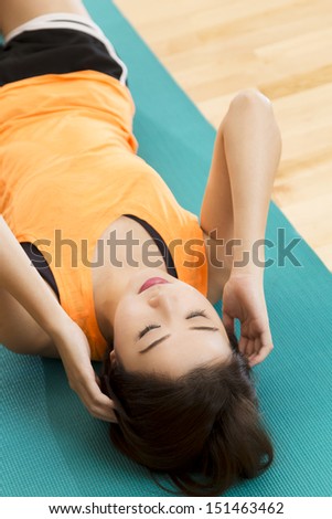 An Asian lady doing her sit ups exercise in a gym