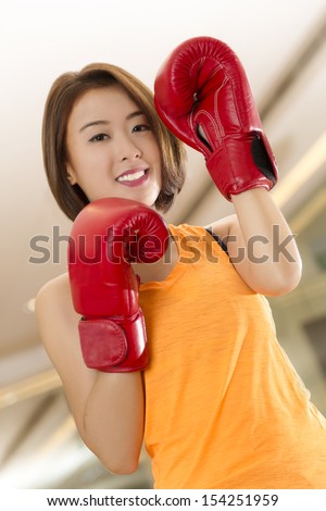 An Asian lady in boxing pose in a gym.