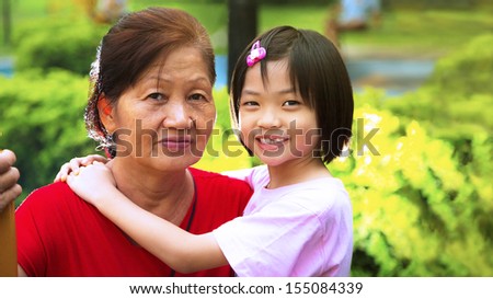 Grand daughter hugging Grandmother in the park.
