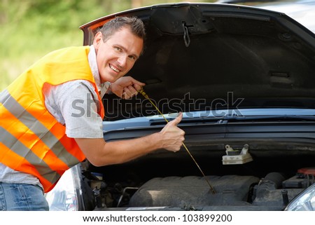 Man checking level of oil on a car engine dipstick