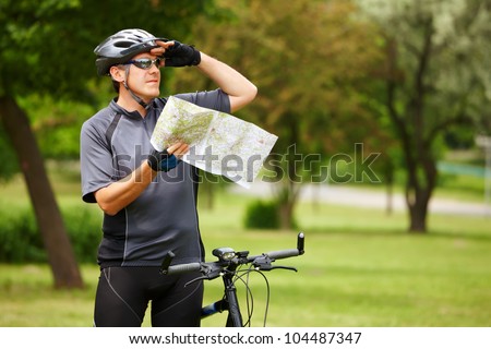 Man on bike checking map and looking around.