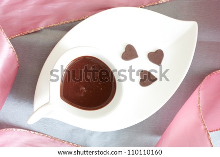 Liquid hot chocolate with little heart shaped chocolates, served in elegant modern style.