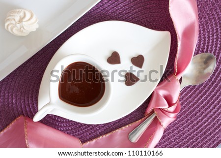 Liquid hot chocolate with little heart shaped chocolates, served in elegant modern style.