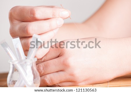 Hand applying acupuncture needle in a point called Hegu.
