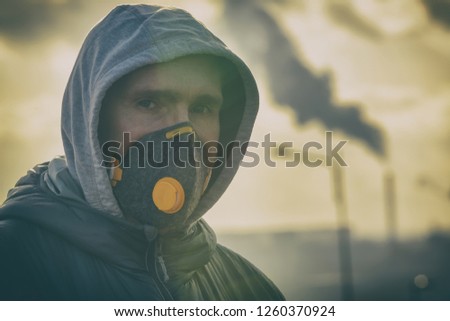 man wearing a real anti-pollution, anti-smog and viruses face mask; dense smog in air