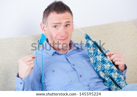Confused man sitting with knitting woll and needles