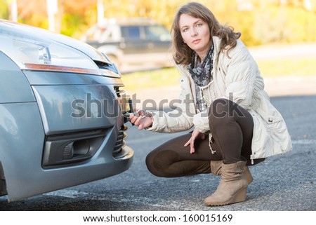 Beautiful woman assembling towing hook to a broken car