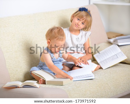 Little boy an girl sitting on the couch and reading books