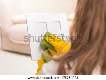 Woman cleaning frame in her home wearing yellow gloves and using cloth