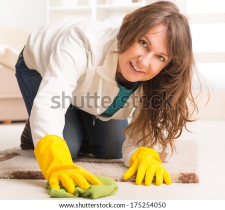 Beautiful young woman cleaning her house with cloth wearing yellow gloves
