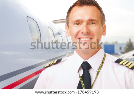 Airline pilot wearing uniform with epaulettes with passenger aircraft in background
