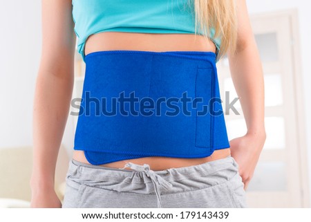Woman wearing neoprene slimming belt at home