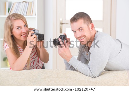 Young couple at home taking pictures with old analog SLR cameras