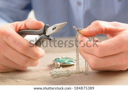 Man repairing or creating jewelry silver chain with pliers