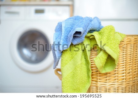 Dirty clothes basket with towels waiting for laundry with washing machine in backround
