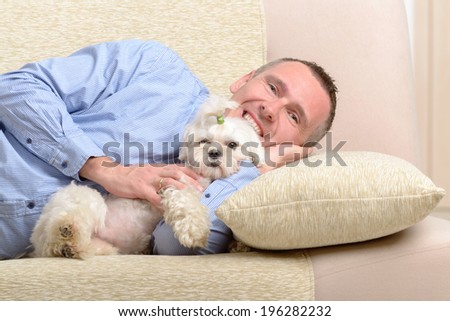 Little dog maltese with his owner on the sofa in home