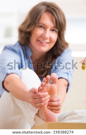 Beautiful woman doing feet reflexology or zone therapy at home