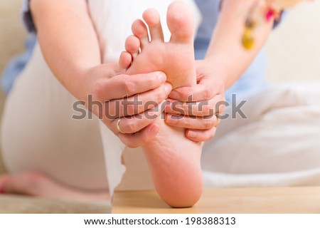 Hands doing feet reflexology or zone therapy at home