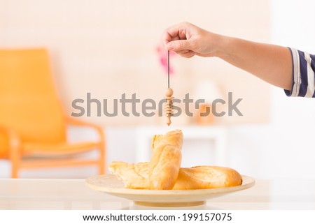Hand with pendulum dowsing over food to check its quality