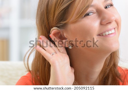 Young, smiling woman wearing deaf aid