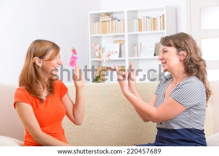 Smiling deaf woman learning sign language and talking with her teacher