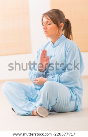 Beautiful woman meditating wearing professinal, oryginal chinese clothes at gym