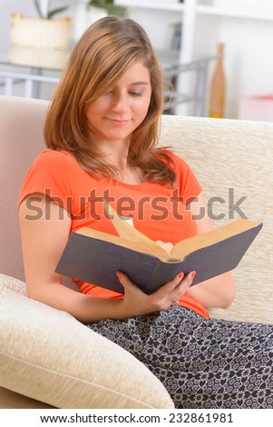 Young woman student reading a book in home