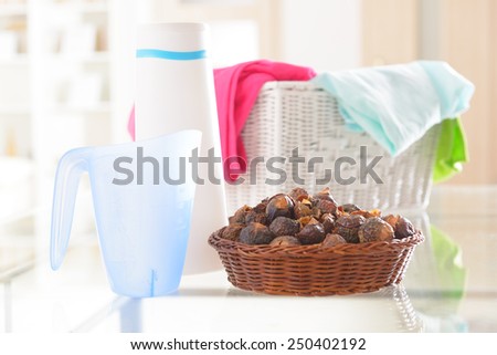 Basket full of soap nuts, natural bio detergent and laundry with bottle and scoop