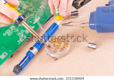 Serviceman soldering PCB with soldering iron in the service workshop