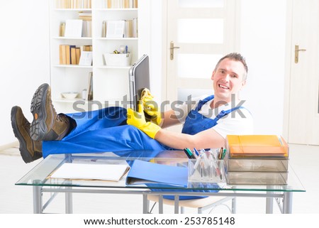 Smiling man cleaner wiping laptop at the office