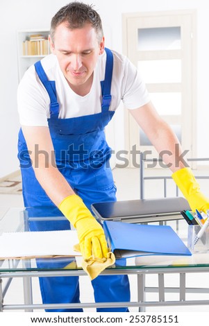 Smiling man cleaner wearing yellow gloves and cleaning office