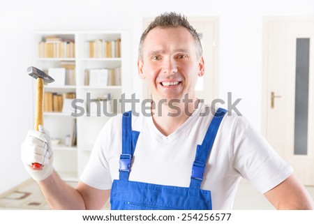 Smiling man with hammer at home or office wearing protective suite
