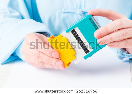 Hand holding automatic stamp over blank paper