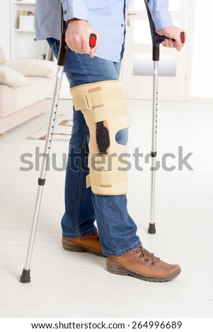 Man with leg in knee cages and crutches for stabilization and support