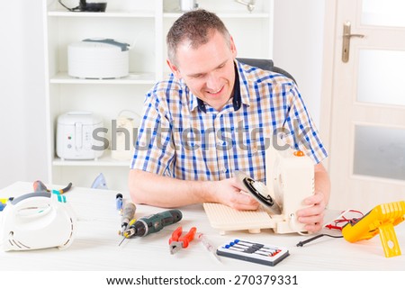 Man repairing a slicing machine at home appliance service workshop