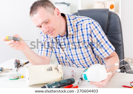 Smiling man repairing held food mixer at home appliance service workshop