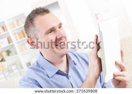 Smiling Deaf man talking using tablet at home