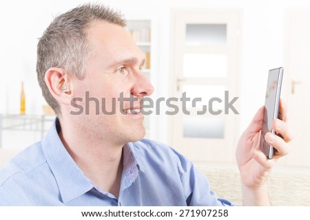 Smiling Deaf man talking using mobile phone at home