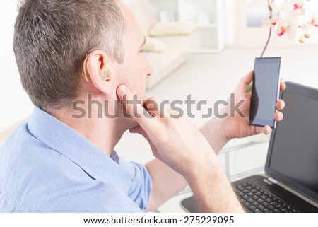 Hearing impaired man working with laptop and mobile phone at home or office