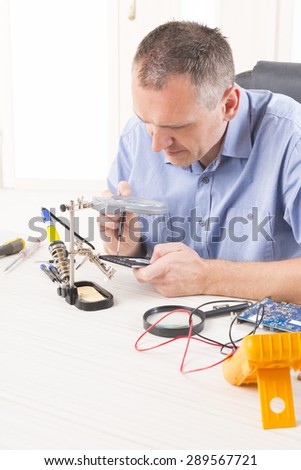 Serviceman repairing mobile phone in the electronic workshop