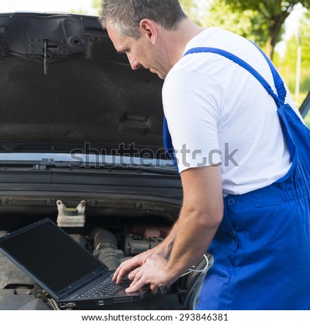 Mobile car service engineer checking car with his laptop on the road