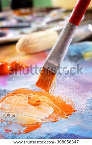 Professional acrylics orange paint on canvas and loaded brush